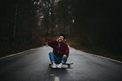 Portrait of man sitting on road in forest