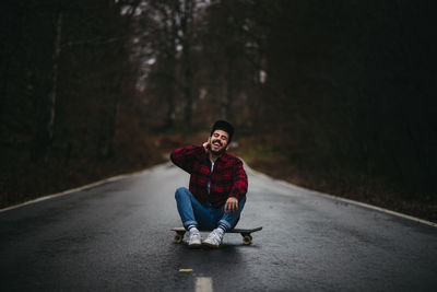 Portrait of man sitting on road in forest