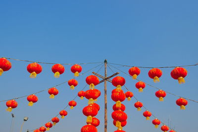 Low angle view of chinese lanterns hanging against clear blue sky