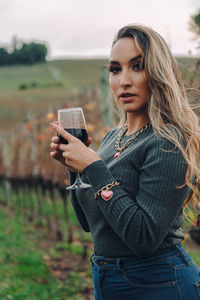 Portrait of young woman holding smart phone while standing on land