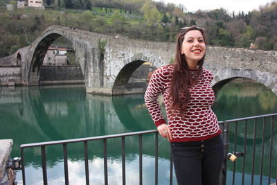 Young woman standing on footbridge over water