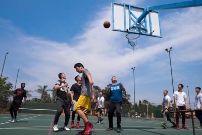 Men playing with basketball hoop against sky