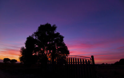 Silhouette trees on landscape against sky at sunset