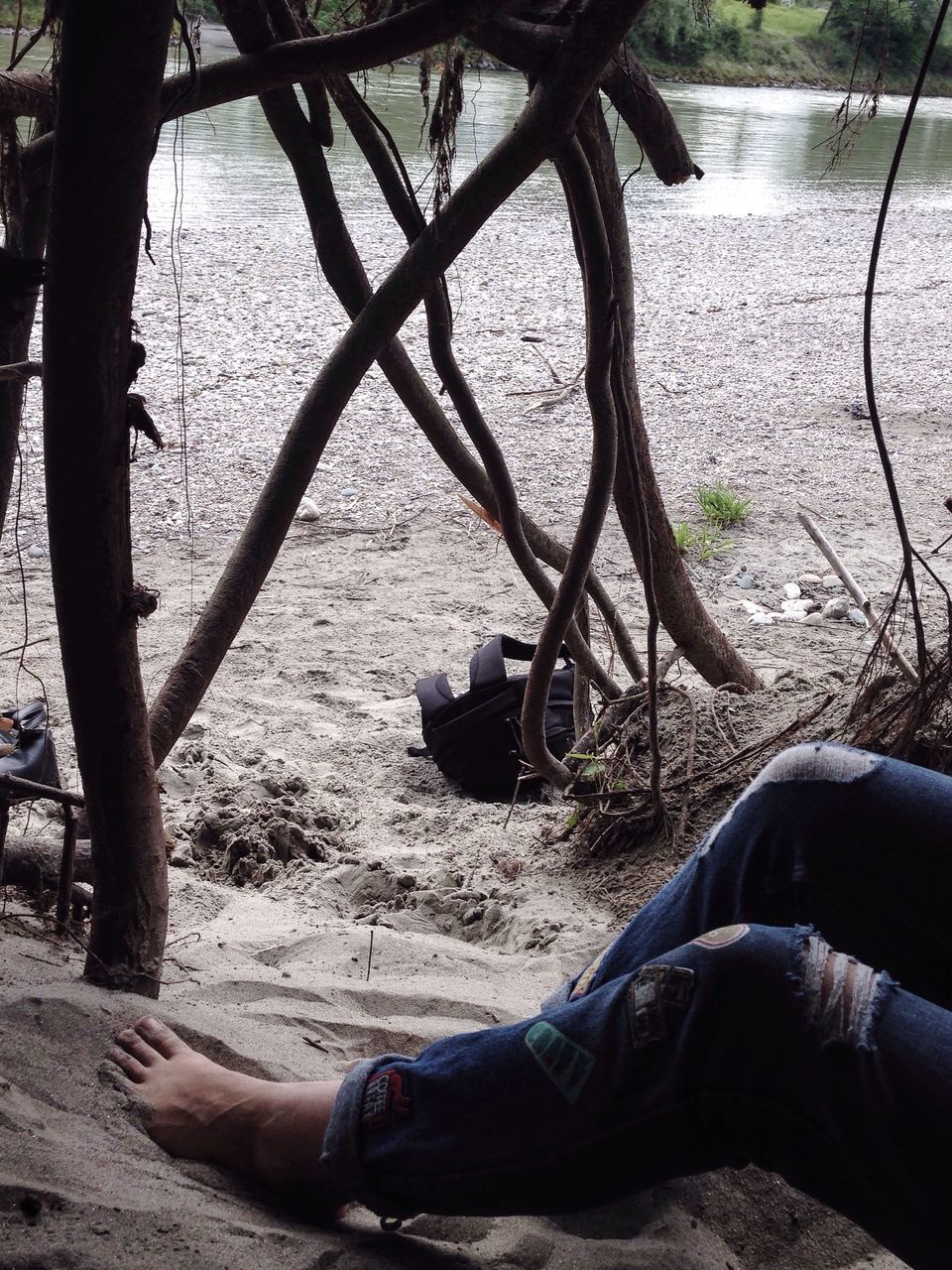 low section, water, person, leisure activity, relaxation, lifestyles, lake, tree, personal perspective, lakeshore, sitting, nature, sand, tranquility, men, beach, vacations