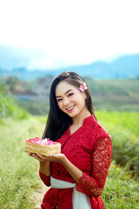 Portrait of an indonesian woman, wearing a red balinese kebaya.