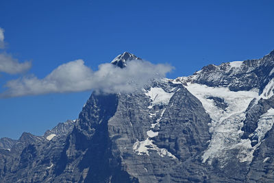 Low angle view of snowcapped mountains against blue sky