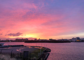 Scenic view of river against dramatic sky during sunset