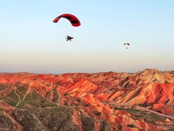 People paragliding over mountain against sky