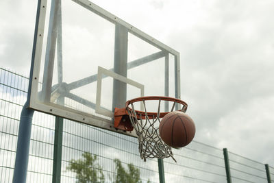 Throwing ball into hoop. basketball flies into net. basketball details. sports ground on cloudy day.