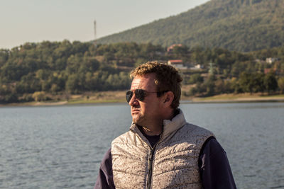 Portrait of young man standing against lake