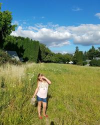 Rear view of boy standing by tree against sky