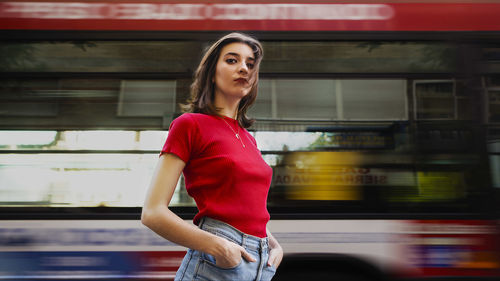 Portrait of young woman standing against bus