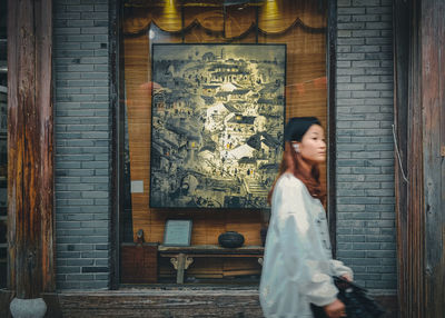 Side view of woman standing against wall