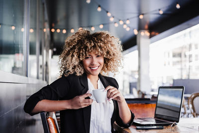 Confident hispanic business woman in cafe working on laptop and mobile phone. tech and lifestyle