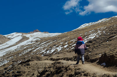 Rear view of woman walking on mountain against sky