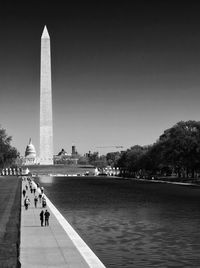 People walking in front of historical building against clear sky