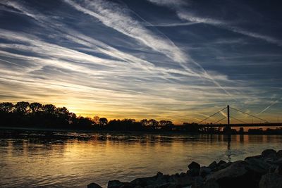 Silhouette bridge over sea against sky during sunset