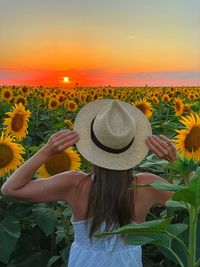 Rear view of woman wearing hat against sky during sunset