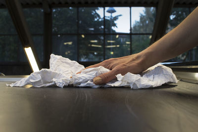 Cropped hand of woman cleaning table with textile