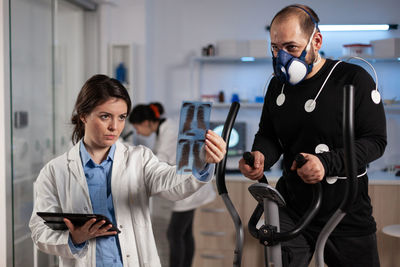 Doctor holding medical x-ray while training patient