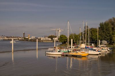 Boats moored at harbor against sky