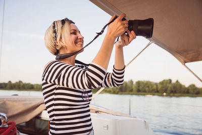 Pretty woman with camera taking pictures on a yacht