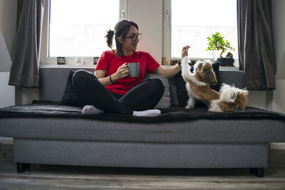 Man with dog sitting on sofa at home