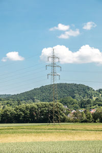 Electricity pylon on field against sky