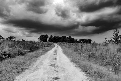 Road amidst field against sky