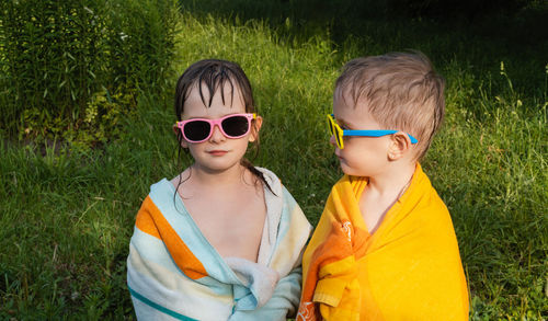 Wet cheerful children in sunglasses in a towel. boy looks at the girl, and she is in the frame. 