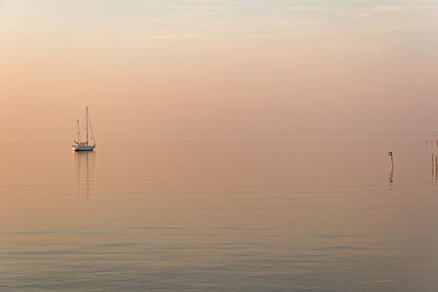 Sailboat sailing on sea against sky during sunset