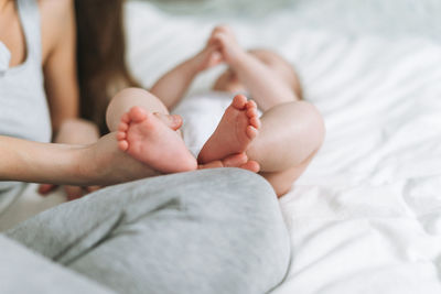 Young mother having fun with cute baby girl on bed with white linen, natural tones, love emotion