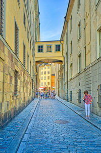 Rear view of people walking on street amidst buildings in city