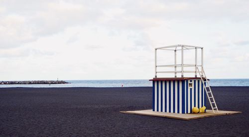 Lifeguard hut on beach against sky