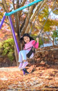 Portrait of smiling girl on swing in playground