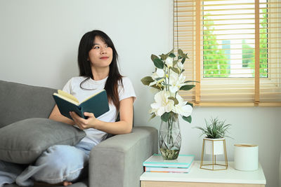 Young woman sitting on sofa at home