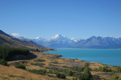 Scenic view of lake and mountains against clear blue sky