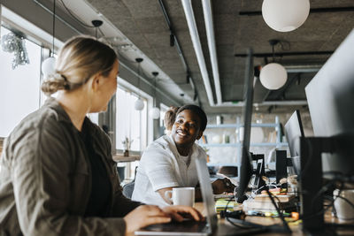 Female programmer talking with male colleague while working in tech startup office
