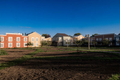 Houses on field against clear blue sky