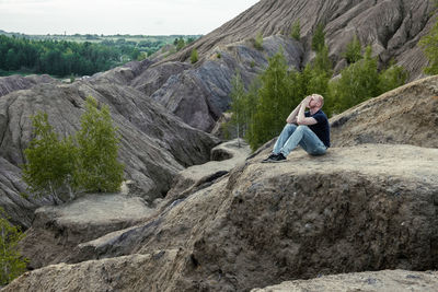 Rear view of man sitting on rock