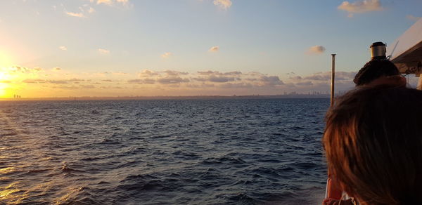 Rear view of woman against sea during sunset