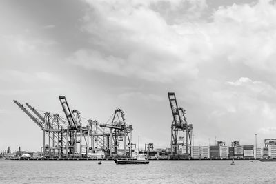 Cranes at commercial dock against sky