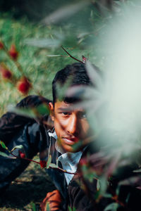 Portrait of young man sitting by plants