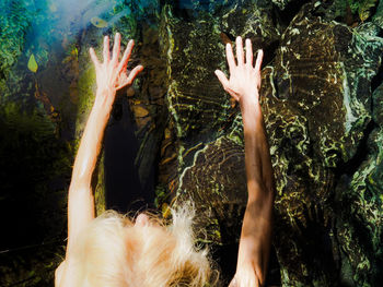 Midsection of woman with arms raised against trees