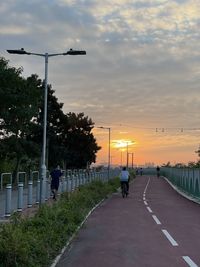 Rear view of man on street against sky at sunset