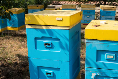 Several plastic/styropharm bee hives, placed among trees in village backyard