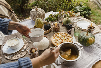 Hands of woman pouring porridge at autumnal table