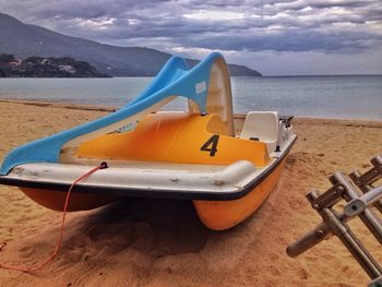 Close-up of boat moored on beach against sky