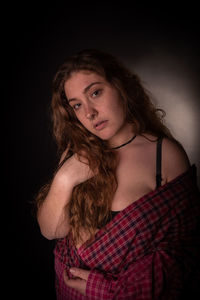 Portrait of seductive young woman over black background