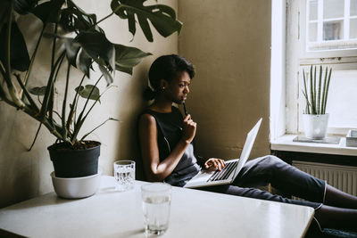 Thoughtful businesswoman using laptop while sitting in office